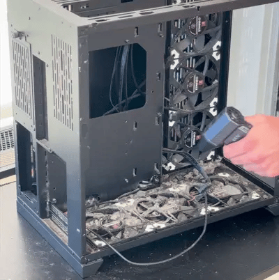 someone using a blowy v3 power blower blowing dust out of a dirty pc case