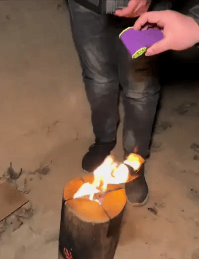 two people using a blowy v3 power blower to fan a camp fire